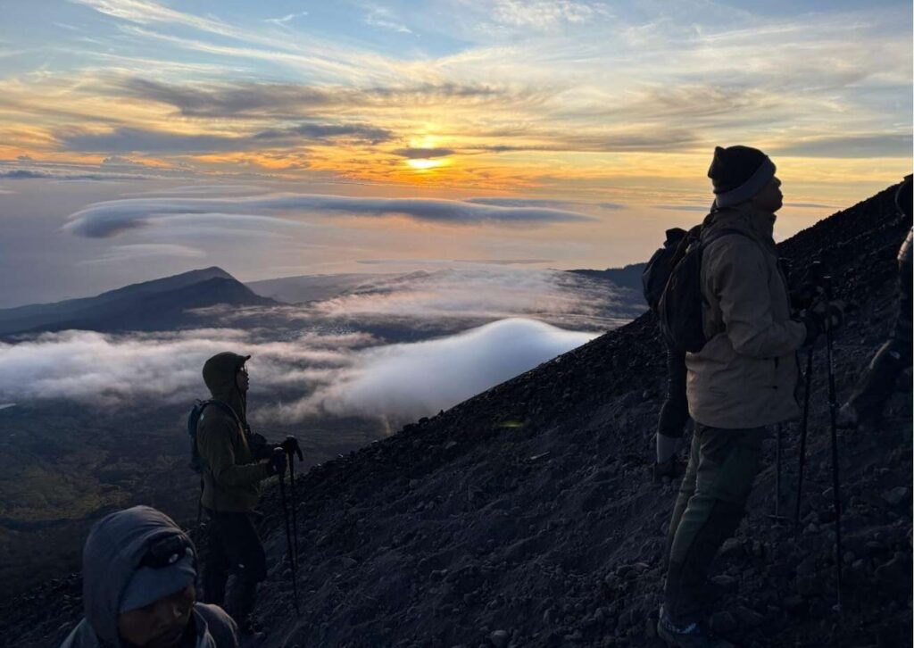 Climbing Mount Rinjani summit view with hikers overlooking Segara Anak crater lake in Lombok Indonesia