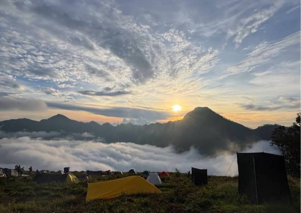 Golden sunset view at Sembalun campsite on Mount Rinjani with colorful tents, mountain landscape, and hikers enjoying the peaceful evening atmosphere.