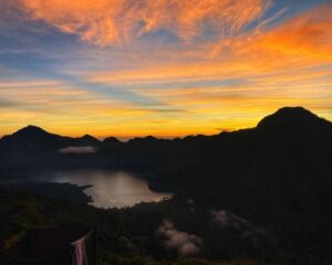 Golden sunset view at Mount Rinjani crater rim with dramatic volcanic landscape and colorful evening sky in Lombok, Indonesia.